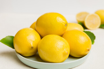 Fresh cutted lemon and whole lemons over round plate on colored background. Food and drink ingredients preparing. healthy eating theme top view vith copy space