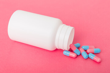 different drugs and health supplement pills poured from a medicine bottle health care and medical top view on colored background