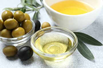 Bowl of fresh olive oil and olives on white background 