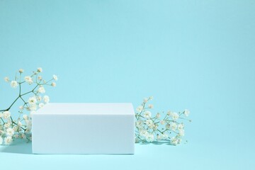 Podium and white gypsophila flowers on a colored background
