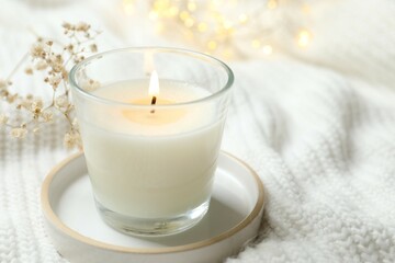 Aromamic candle burning on knitted fabric