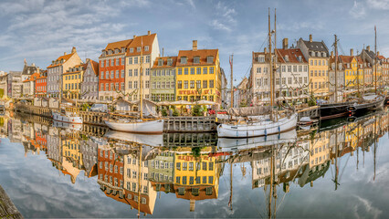 Naklejka premium panorama of colorful houses reflects in the water along the Nyhavn Canal in Copenhagen, November 2, 2024