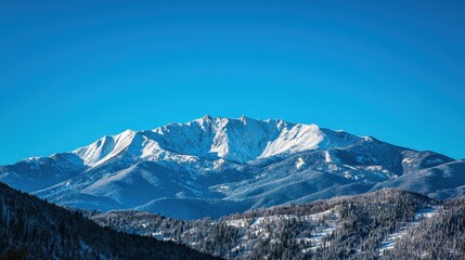Fototapeta premium A stunning snow-capped mountain peaks against a bright blue sky, showcasing serene winter beauty and natural majesty.