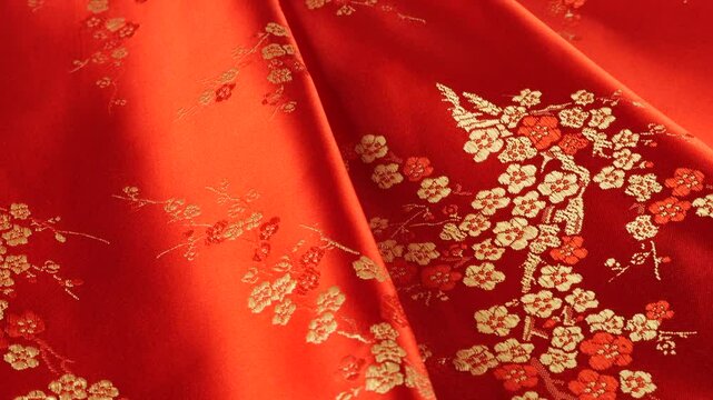 Lustrous red silk textile strawberry shade fabric background with floral embroidery in oriental style with plum blossom flower pattern.