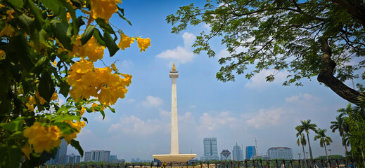 Scenic view of the National Monument or Monas around city skyscrapers under a clear blue sky and sunny day, good for news article