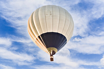 Colorful hot air balloon flying over blue sky with white clouds