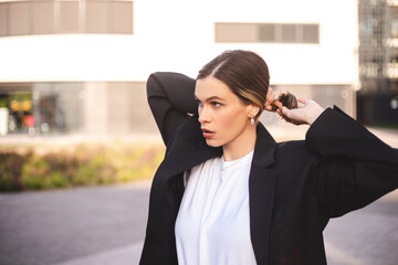 Close-up portrait shot of a young blonde business lady do hair. Woman standing near business centre...