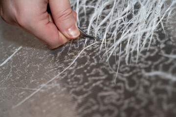 main d'un créateur de mode insérant des plumes dans un tissus avec sequins, artisan couturier
