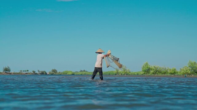 A fisherman throwing a fishing net on the seashore