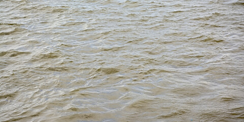 Muddy brown water surface with small waves 