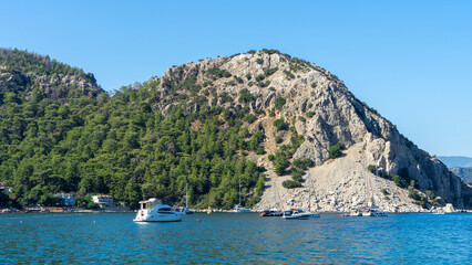 Fototapeta premium View of yachts, marina and promenade in village of Turunc, Turkey. Resort town on Mediterranean Sea. Rock near the village of Turunc, Turkey