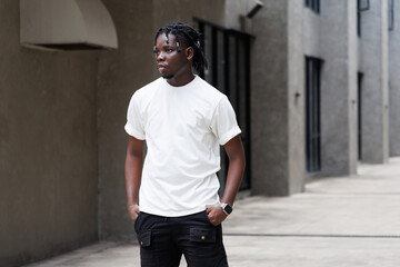 Candid of African man model with dreadlocks hairstyle wearing white t-shirt standing in the city