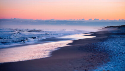 Obraz premium An unexpected winter beach scene with frosty sand and gentle waves rolling in, the morning light casting a soft glow over the cold yet serene landscape.