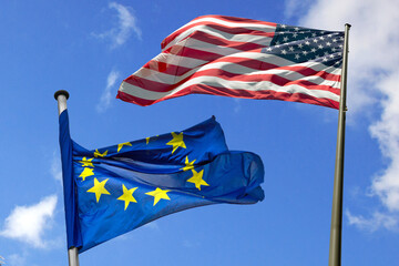 gegeneinander wehende, kämpfende US- und EU-Flaggen