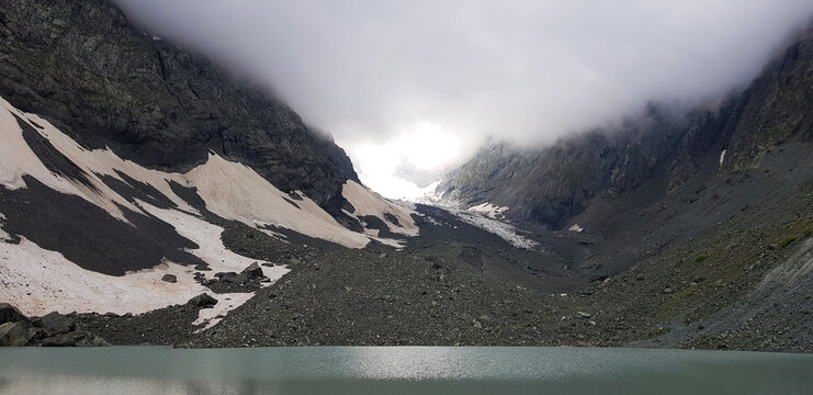 Clouds over a mountain lake; Lake in the mountains; Rocky mountains with clouds; Chaukhi Mountain, Georgia