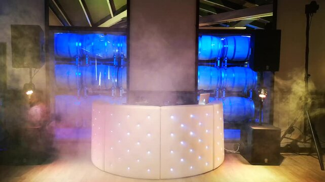The DJ setup is ready for the evening on fire in front of wine barrels in a reception room with an industrial laser beam.