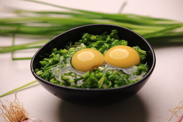 bowl of egg yolks isolated on white background, top view with green vegetables.close up image of two eggs yolk in a bowl are one of the food ingredients on the restaurant table in the kitchen .