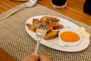 A dining scene with fried chicken wings, dipping sauce, and a beverage on the table in cafe.