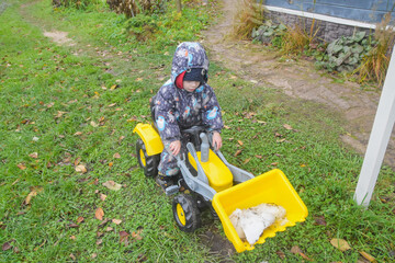 a child boy on a wheeled bulldozer tractor removes snow with a snow plow, photo without filters