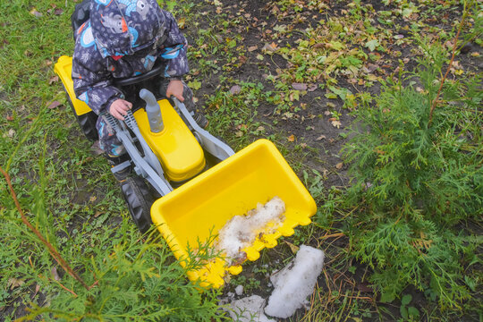 a child boy on a wheeled bulldozer tractor removes snow with a snow plow, photo without filters