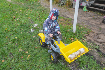 a child boy on a wheeled bulldozer tractor removes snow with a snow plow, photo without filters