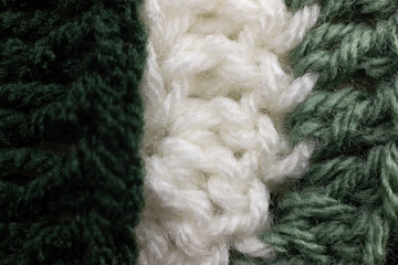 close-up of vertical rows of crochet stitches in a sage green, hunter green and white blanket,...