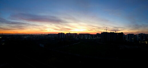 Fototapeta premium Sun goes down. Early morning scene with silhouette dark city. Beautiful colors of sky captured during sunset from Ivano frankivsk, Ukraine.