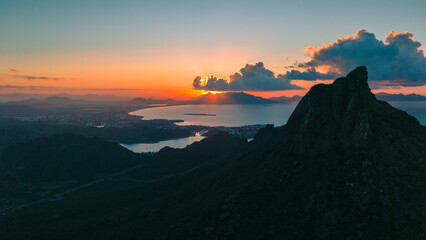 Sunrise from the peak of Tetakawi Mountain overlooking the bay of San Carlos Sonora, Mexico. The rising sun on the horizon paints the sky in warm tones.