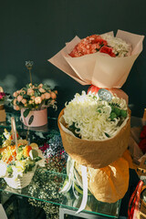 Close-up of vibrant floral bouquets on display, featuring fresh chrysanthemums, roses, and assorted seasonal flowers arranged in paper wraps and baskets under soft sunlight