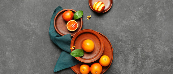 Plates with tasty blood oranges on dark background
