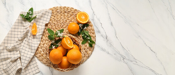 Basket of oranges with blooming branches on white table