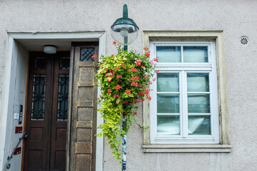 Blumenampel an Straßenlaterne vor historischem Haus mit Holztüre und Sprossenfenstern in Reutlingen