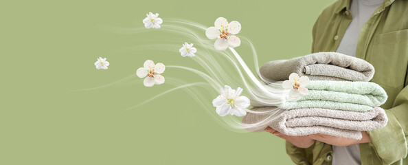 Woman holding stack of clean soft towels on green background