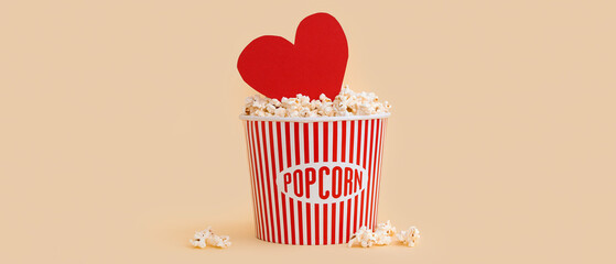 Bucket of popcorn and paper heart on yellow background. Valentine's Day celebration