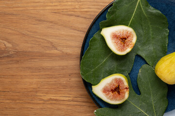 Fresh Figs and Leaves on Blue Plate with Wooden Background
