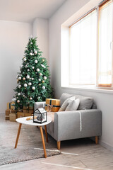 Interior of festive living room with grey sofa and gift boxes under Christmas tree
