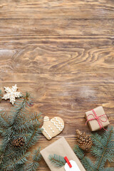 Christmas tree branches with gift boxes and cookies on wooden background