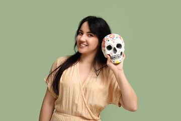 Beautiful young woman with painted skull on green background. Mexico's Day of the Dead