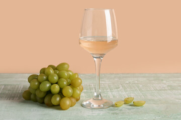 Glass of tasty wine and grape on green wooden table