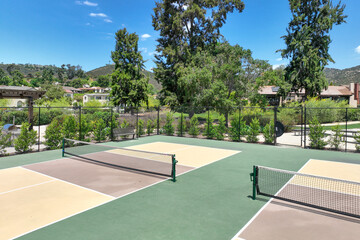 Aerial view of a pickle ball complex with courts beside a playground in a suburban park in San Diego