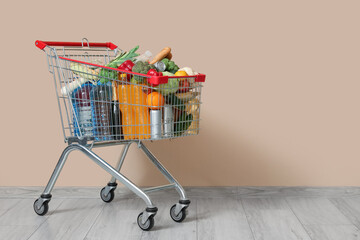Shopping cart full of food near beige wall