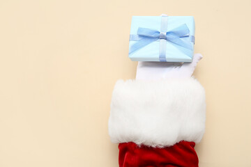 Santa Claus with blue gift box on beige background