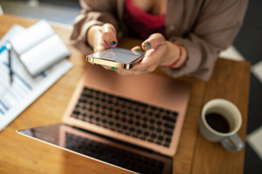 Young woman using smartphone and laptop at home workspace