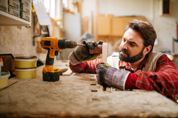 Fototapeta premium Mature carpenter working in his woodworking workshop