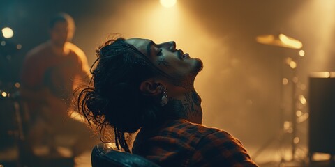 Naklejka premium Tattooed Man Leaning Back in Chair Under Stage Lights
