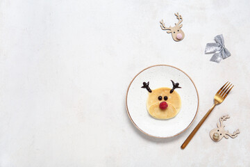 Plate with pancake in shape of reindeer on white background. Christmas celebration