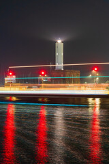 Scena serale ritatta con tempi lunghi del faro di Marina di Ravenna illuminato sul canale