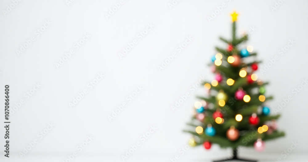 Poster a christmas tree with colorful baubles and blurred shiny lights stands against a plain white backdro