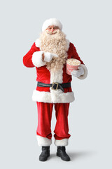 Santa Claus pointing at tasty popcorn on white background