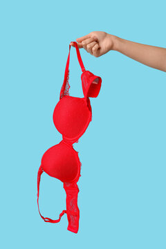 Female hand with sexy red bra on color background, closeup